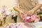 Close up of young woman arranging beautiful pink rose flower bouquet vase on table