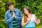 Close up of young woman with a disgusting face holding in her hands a letter, with a worried boyfriend looking the girl