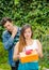 Close up of young woman doing a face of detesting the gift she is holding in her hands, with thoughtful boyfriend behind