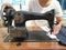 Close-up of young woman Dressmaker or seamstress sitting and sews on old sewing machine. Tailor making a garment in her workplace.