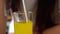 Close up, young woman drinking orange soda in kitchen. Female enjoying carbonated lemonade sipping through straw.