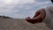 Close up of young woman hand with handful of sand falling and flying in the wind. cloudy moody day, concept of melancholy and