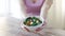 Close up of young woman hands showing salad bowl