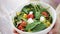 Close up of young woman hands showing salad bowl