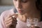 Close up young woman holding pill and glass of water
