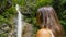 CLOSE UP: Young woman looks up at the breathtaking waterfall in Logar valley.