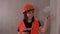 Close up of young woman in overalls smiling and showing thumb up. Female construction worker with spatula and putty on