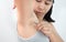 Close up of young woman plucking armpit underarm with tweezers  on grey background. Concept of Hygiene skin body care and