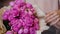 Close-up of a young woman\'s hand touching a bouquet of pink roses.