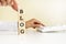 Close up young woman`s hand in white shirt wooden block cube for blog wording on white table floor