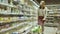 Close-up of a young woman's hands moving a grocery cart through the aisles of a supermarket, the concept of sale and