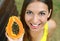 Close up of young woman showing papaya healthy fruit outdoor