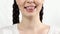 Close up of young woman smiling shows teeth ligature braces. White background. Concept of orthodontic treatment