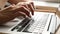 Close-up of a young woman typing on a laptop keyboard. Work.