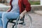 Close up of a young woman in a wheelchair while walking in a park on a sunny day. Recovery and healthcare concepts