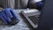 Close up of a young woman working at home at the table in gloves. Quarantine, self-isolation. Girl look at a laptop computer. Free