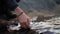 Close-up on your hands. A hiker puts his hand down into a cold river. Close-up.