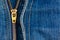 Close up of a zipper over blue denim
