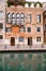 Close-ups of building facades in Venice, Italy. An ancient stone three-storey house on the banks of Venetian Canal