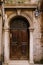 Close-ups of building facades in Venice, Italy. An old, gloomy wooden door, brown. Stone arched doorway. The facade of a