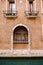 Close-ups of building facades in Venice, Italy. A stone arch above a wooden window on the facade of building. White