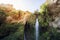 Close uup of Great Falls Shulamit falling from the top of a mountain with green trees and bushes. Ein Gedi - Nature Reserve and