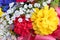 Close view of an assortment of vibrant artificial flowers with a pink ribbon