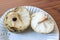 Close view of a broken open cherimoya fruit Annona cherimola on a white fluted plate showing central stem and large black seed