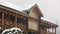 Close view of cottage with mezzanine in mountain village during heavy snowfall with russian style carved wooden facade