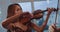 Close view of duet of female violinists performing music at window indoor