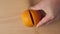 Close view of a hand cutting an orange in half for making fresh juice on the cutting board.