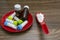 Close view image of Homeopathic medicine substance bottles in red plate and pills in red spoon on wood background