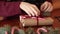 Close view of man`s hands tying a bow on a gifts for Christmas. Male wrapping present boxes in paper adding fir branches