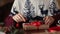 Close view of man`s hands tying a bow on a gifts for Christmas near fireplace, wrapping boxes, decorating with fir