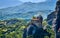 Close view of monastery of St Nicholaos Anapafsas on top of sedimentary pillar, green hills of Meteora valley at midday