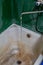 Close view of old stained water tap and rusted bathtub with selective focus and blur