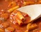 Close view of rigatoni pasta and sausage with a wood spoon