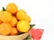 A close view of ripe tangerines in a wooden bowl on a white background