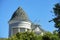 Close view of spire or turrent on house or home with gray roof tiles and white facade exterior with back yard trees and