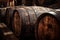 Close view of vintage wooden barrels in dark wine cellar of winery. Old oak casks in underground storage. Concept of vineyard,