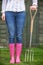 Close Of Woman Wearing Pink Wellingtons Holding Garden Fork