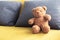 Close â€“ up teddy bear. Teddy with Pillow. They are on yellow  sofa.