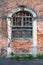 Closed and boarded creepy looking old venetian style red brick abandoned family house entrance covered with dried crawler plants