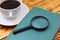 Closed book with a magnifier and a coffee on the background