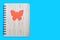 Closed bound notebook with bamboo cover with orange butterfly ornament on a blue background