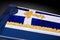 Closed coffin covered with blue and white cloth decorated with Church gold cross on gray luxury background. Close-up.