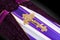 Closed coffin covered with purple and white cloth decorated with Church gold cross on gray luxury background. Close-up.