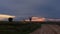 A closed dirt road over a railway crossing with a sunset