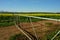 A closed double farm gate with a gravel road and canola fields