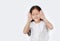 Closed eyes little child girl gestures playing peekaboo over white background with copy space. Kid posture open hands from eyes